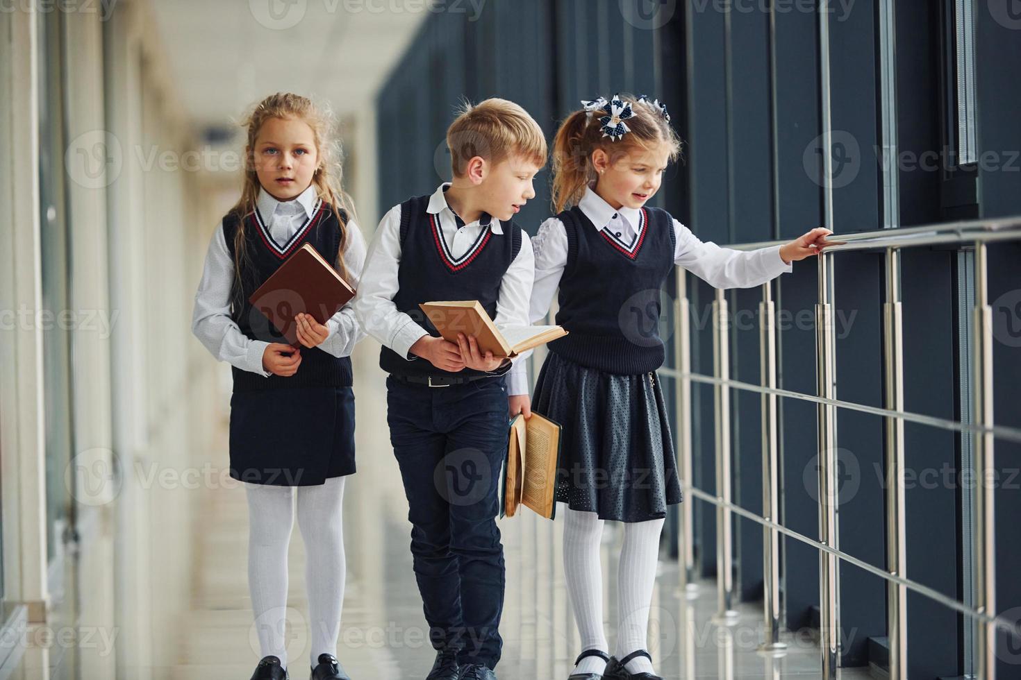 escolares en uniforme junto con libros en el pasillo. concepción de la educación foto