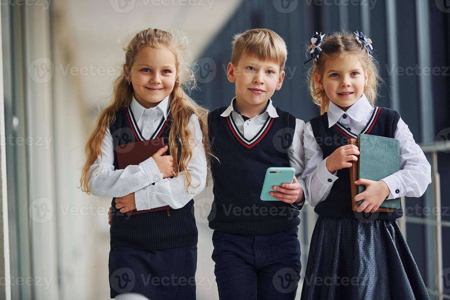 School kids in uniform together with phone in corridor. Conception of education photo