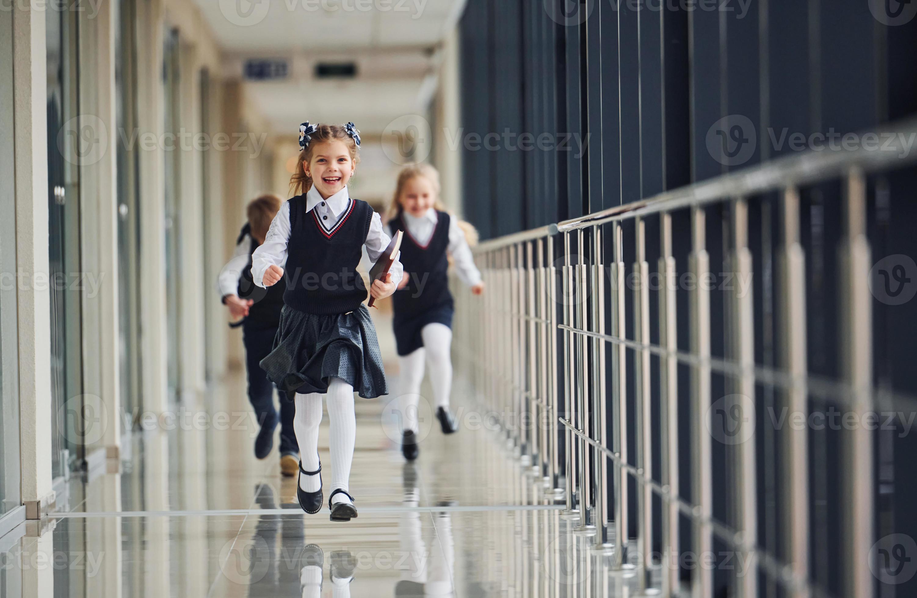 Active school kids in uniform running together in corridor. Conception