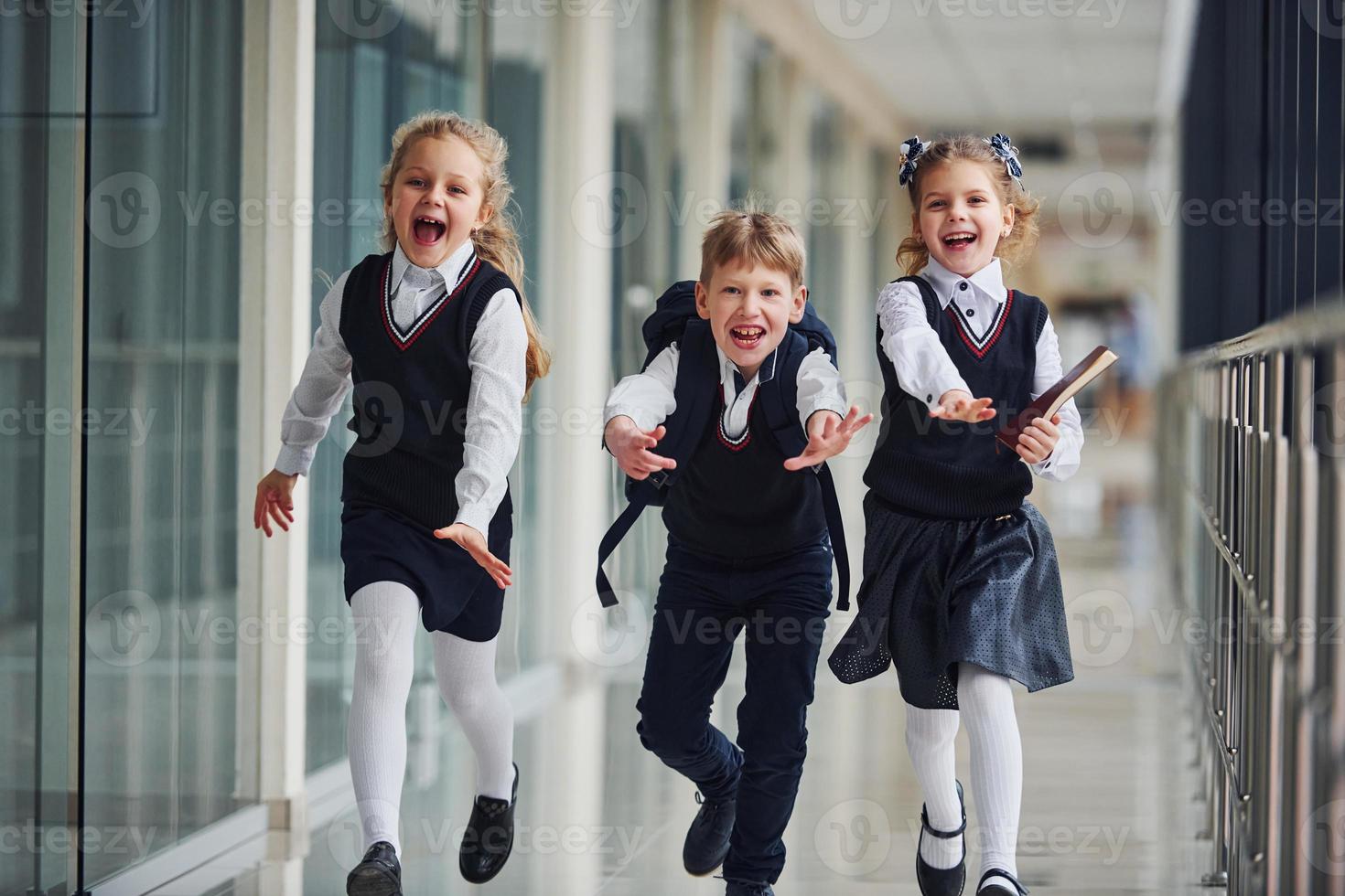 Active school kids in uniform running together in corridor. Conception of education photo
