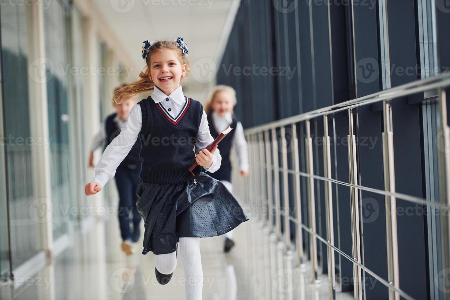 Active school kids in uniform running together in corridor. Conception of education photo