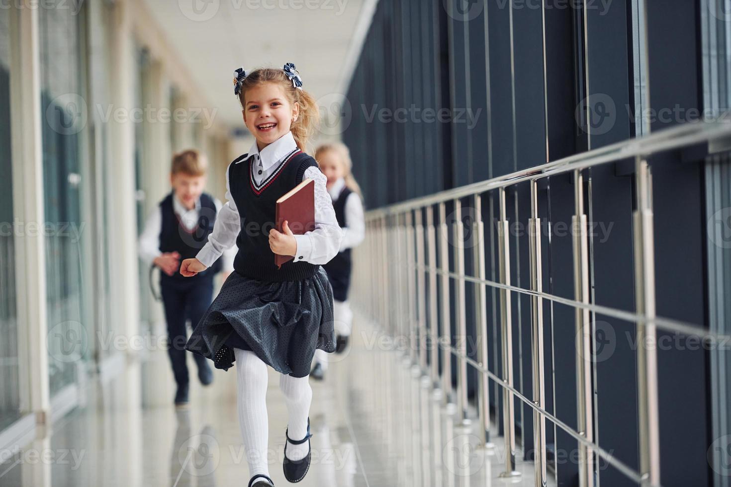 Active school kids in uniform running together in corridor. Conception of education photo