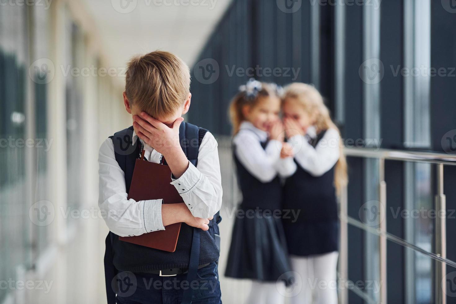 niño pequeño es intimidado. concepción del acoso. niños de la escuela en uniforme juntos en el pasillo foto