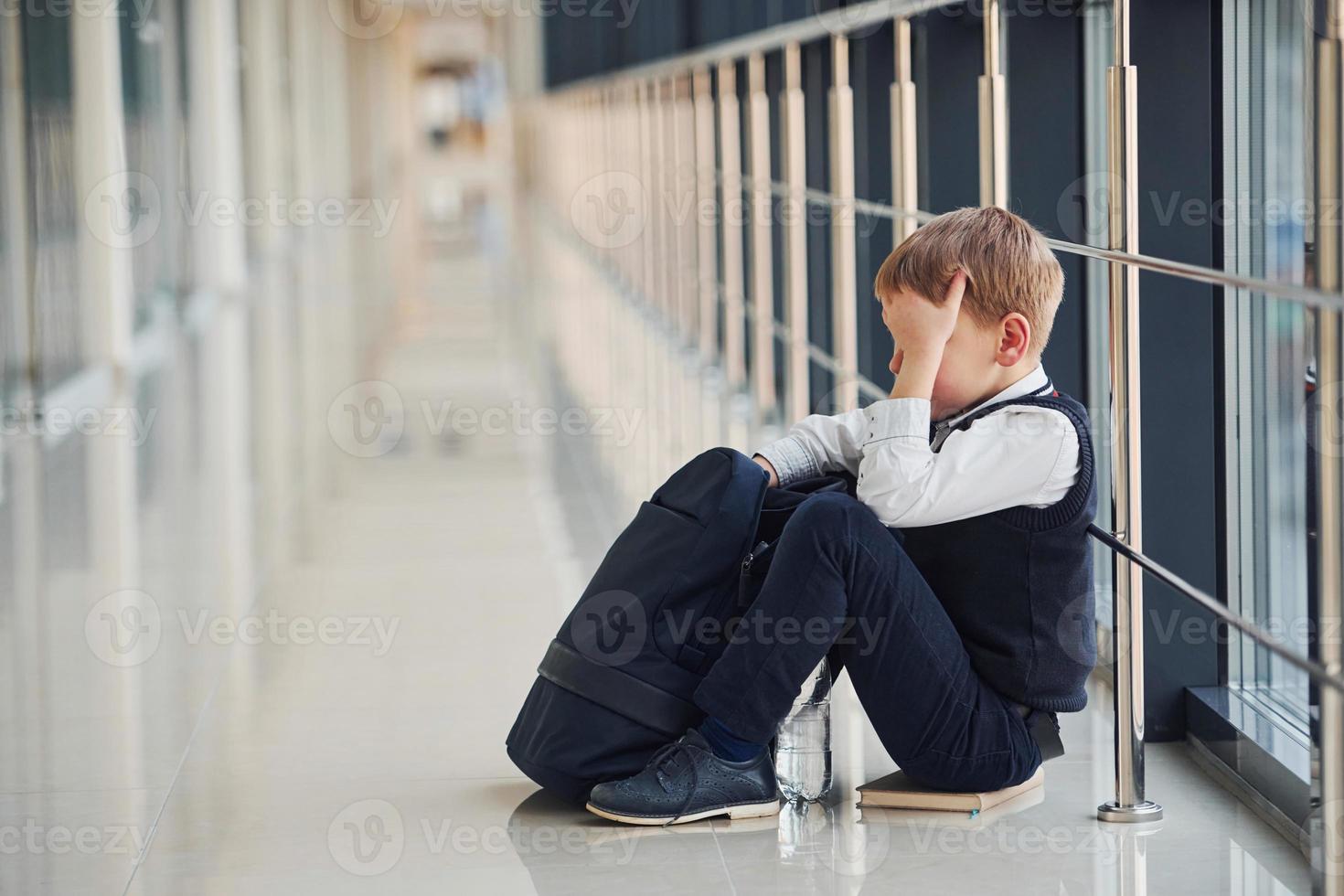 Boy in uniform sitting alone with feeling sad at school ...