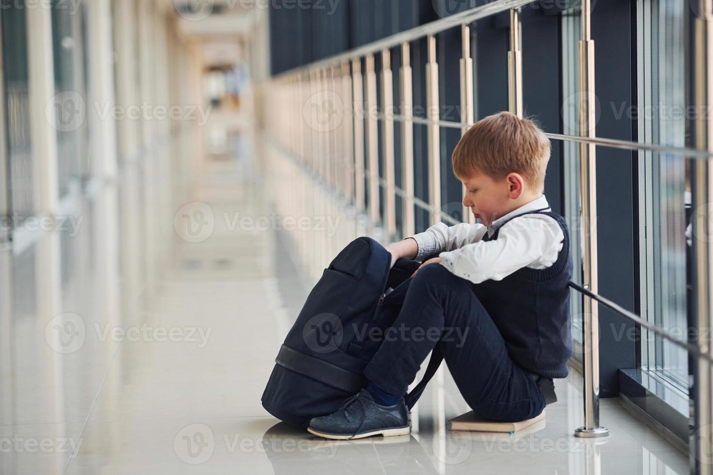 Boy in uniform sitting alone with feeling sad at school ...