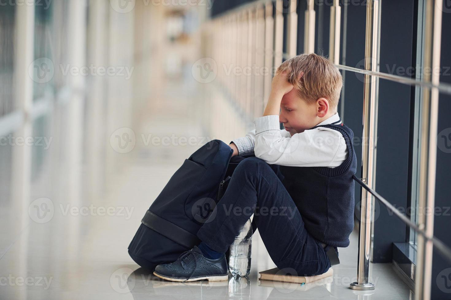 Boy in uniform sitting alone with feeling sad at school. Conception of harassment photo