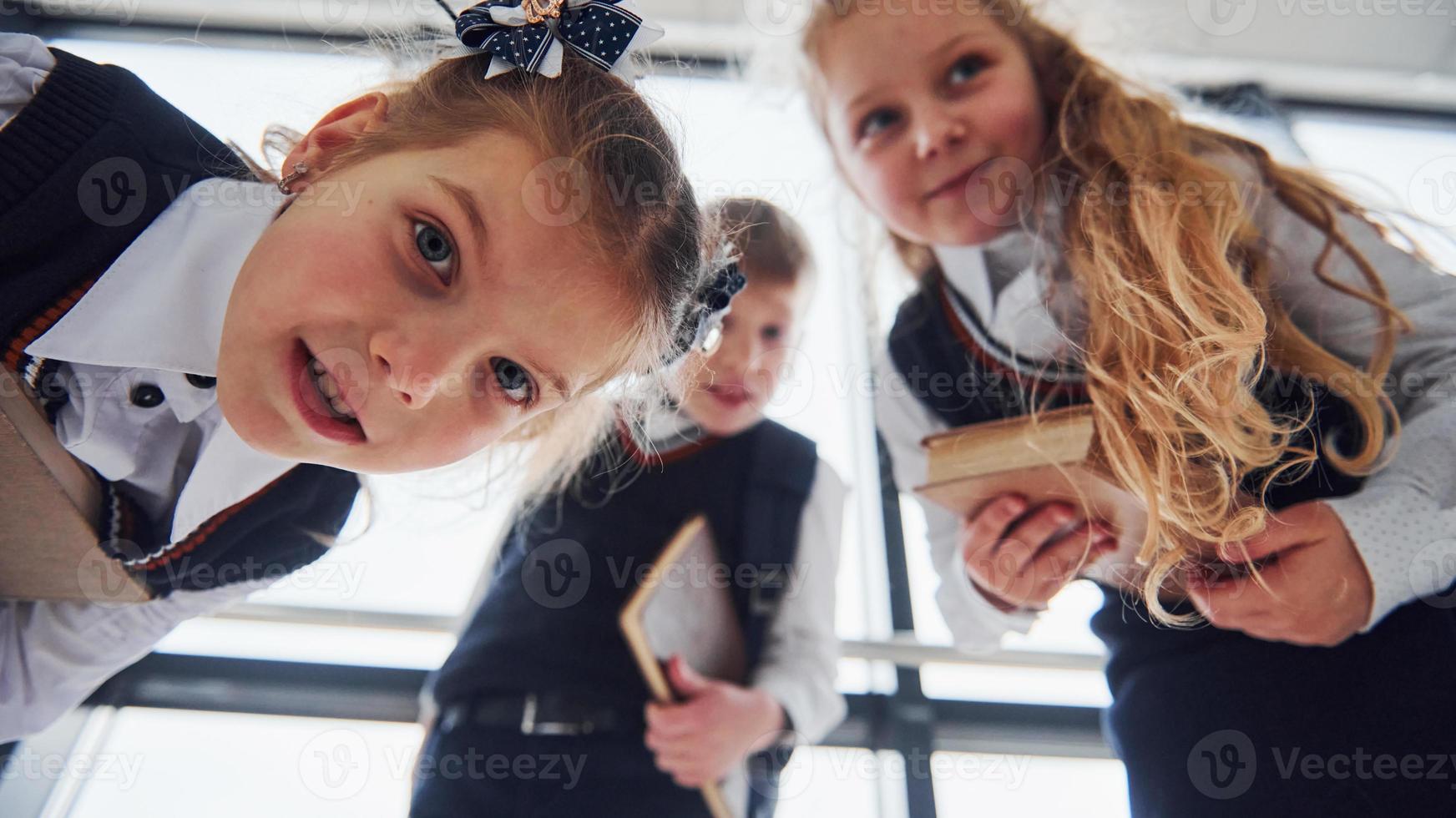 School kids in uniform posing for a camera together in corridor. Conception of education photo