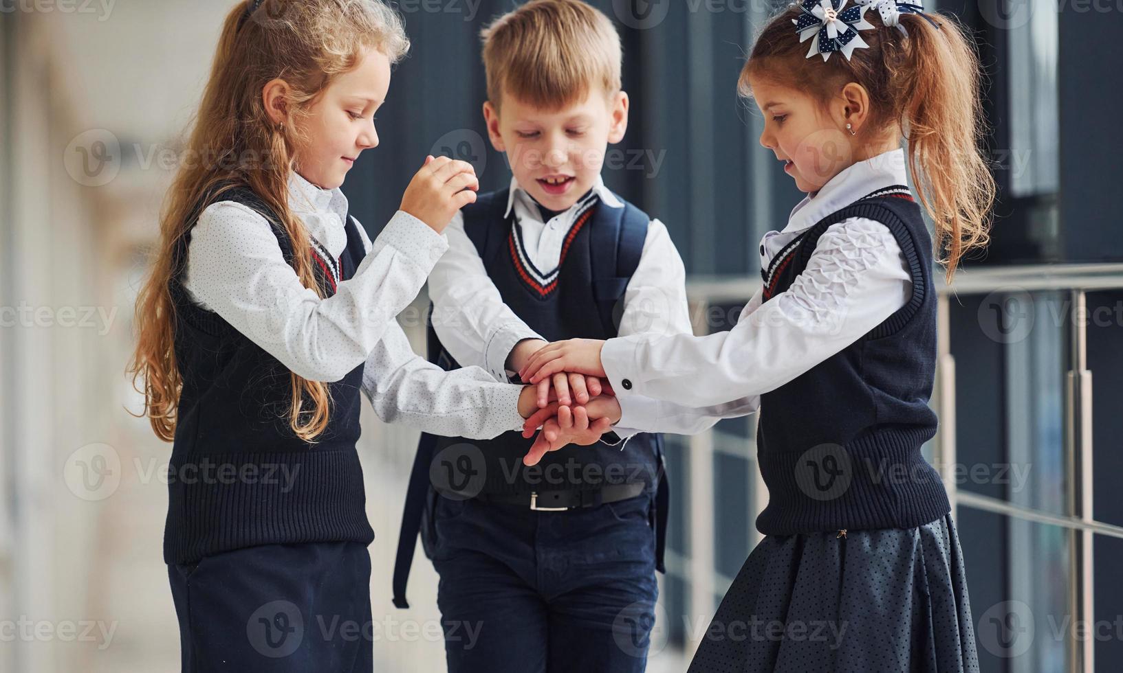 escolares en uniforme haciendo gesto de victoria juntos en el pasillo. concepción de la educación foto