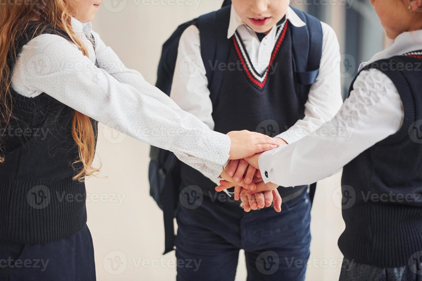 escolares en uniforme haciendo gesto de victoria juntos en el pasillo. concepción de la educación foto