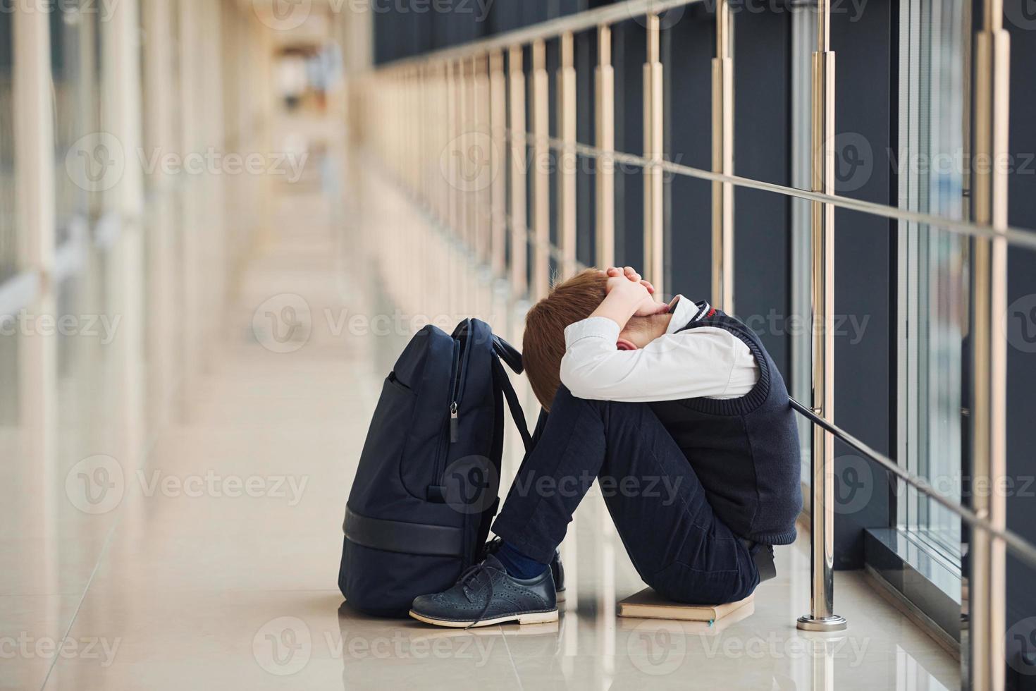 Boy in uniform sitting alone with feeling sad at school. Conception of harassment photo