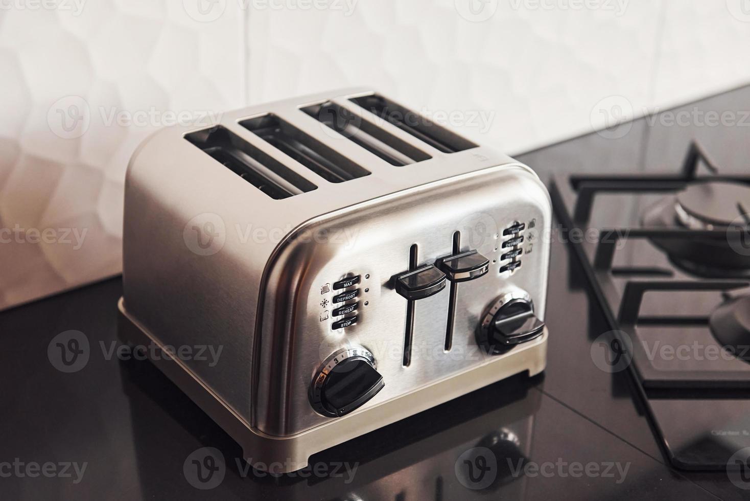 Close up view of silver colored toaster that standing on gas stove indoors in kitchen photo