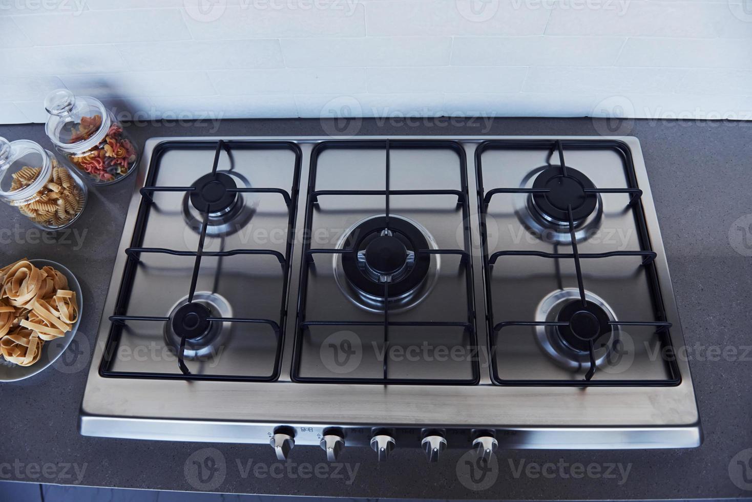 Close up view of top of a gas stove indoors near wall at daytime photo