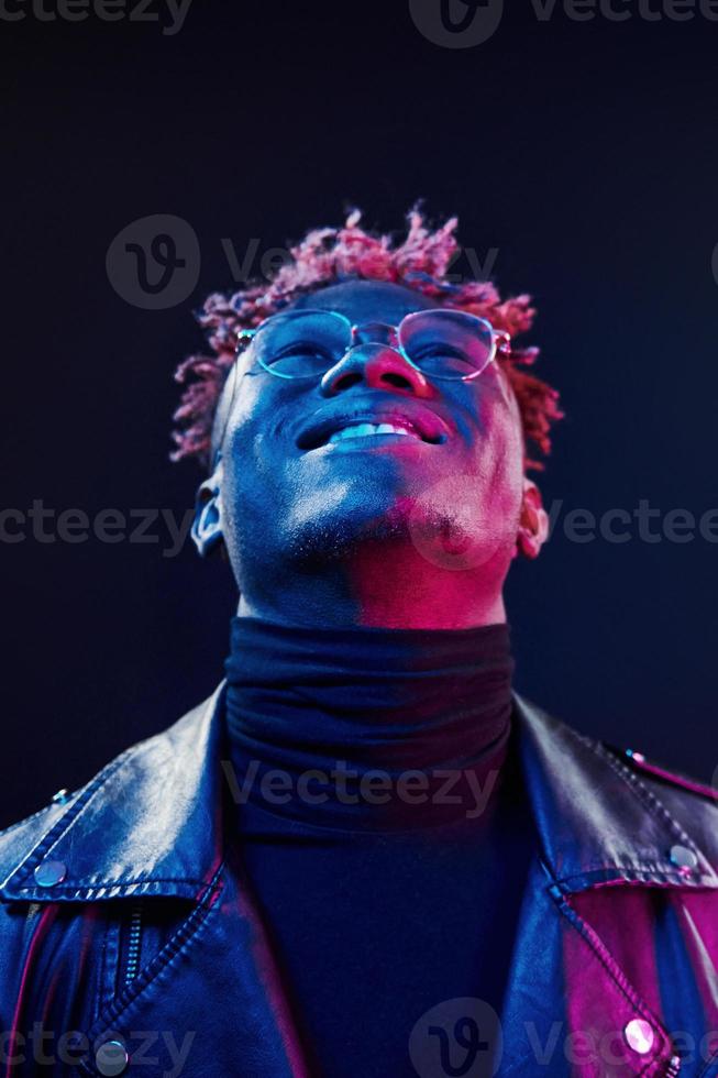 In glasses. Futuristic neon lighting. Young african american man in the studio photo