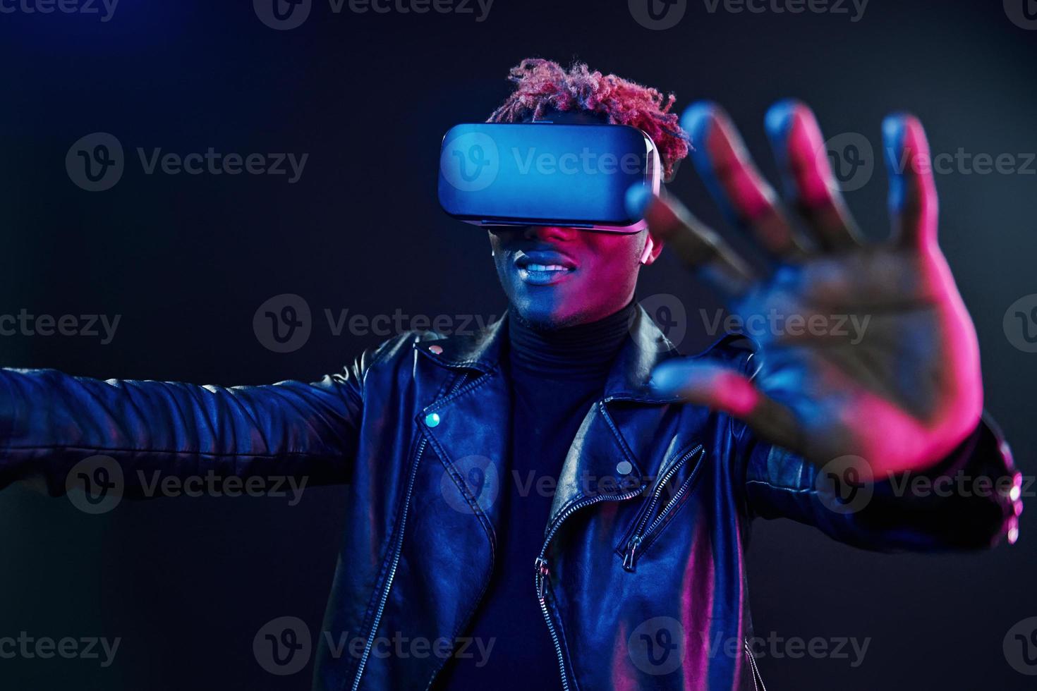 Virtual reality experience. Futuristic neon lighting. Young african american man in the studio photo