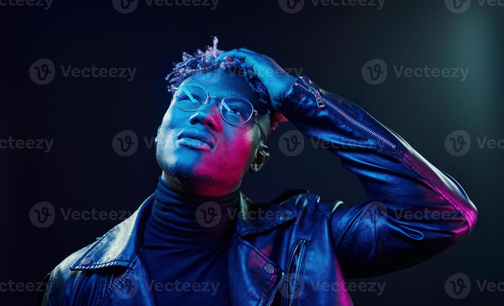 In glasses. Futuristic neon lighting. Young african american man in the studio photo
