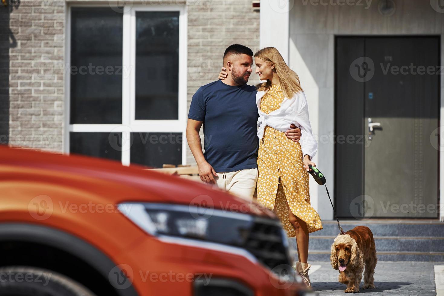 Lovely couple have a walk together with dog outdoors near the car photo