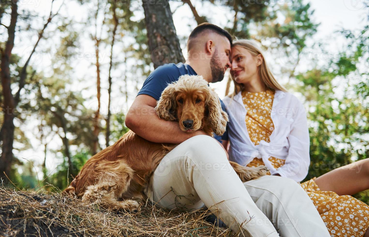 Couple with dog have weekend outdoors in the forest with car behind them photo