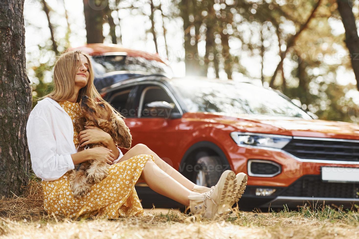 Leaning on the tree. Woman with her dog outdoors in the forest against automobile have good time photo