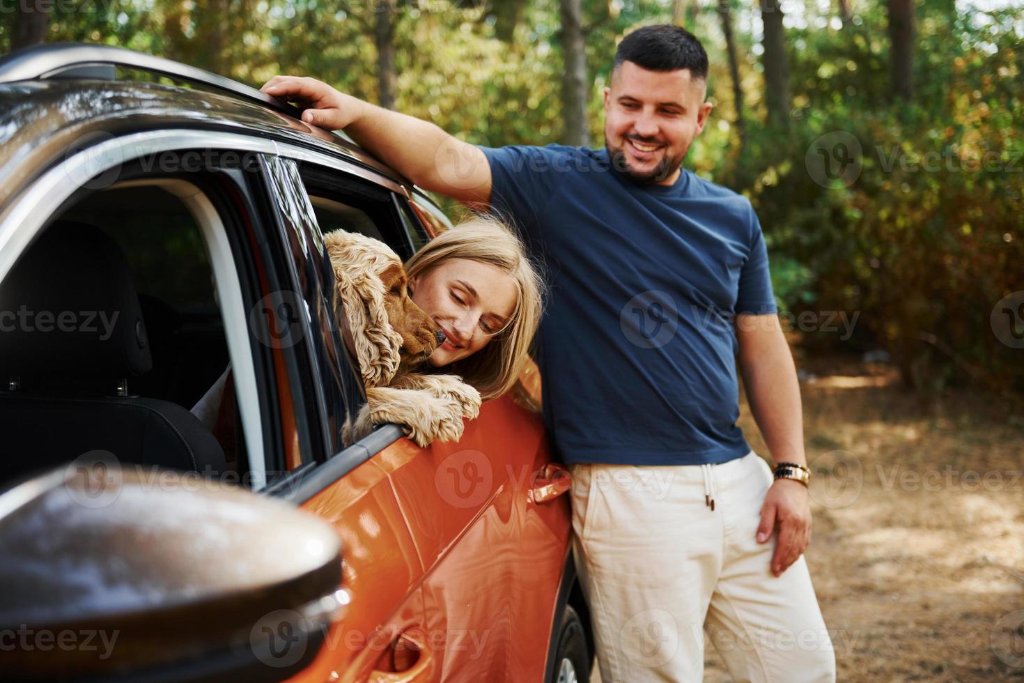 Couple have good time together with dog in car in the forest photo
