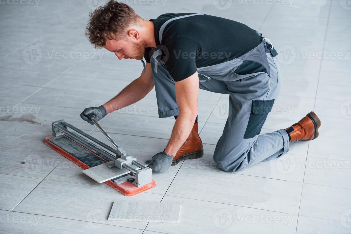 Man in grey uniform installing plate indoors in modern big office at daytime photo