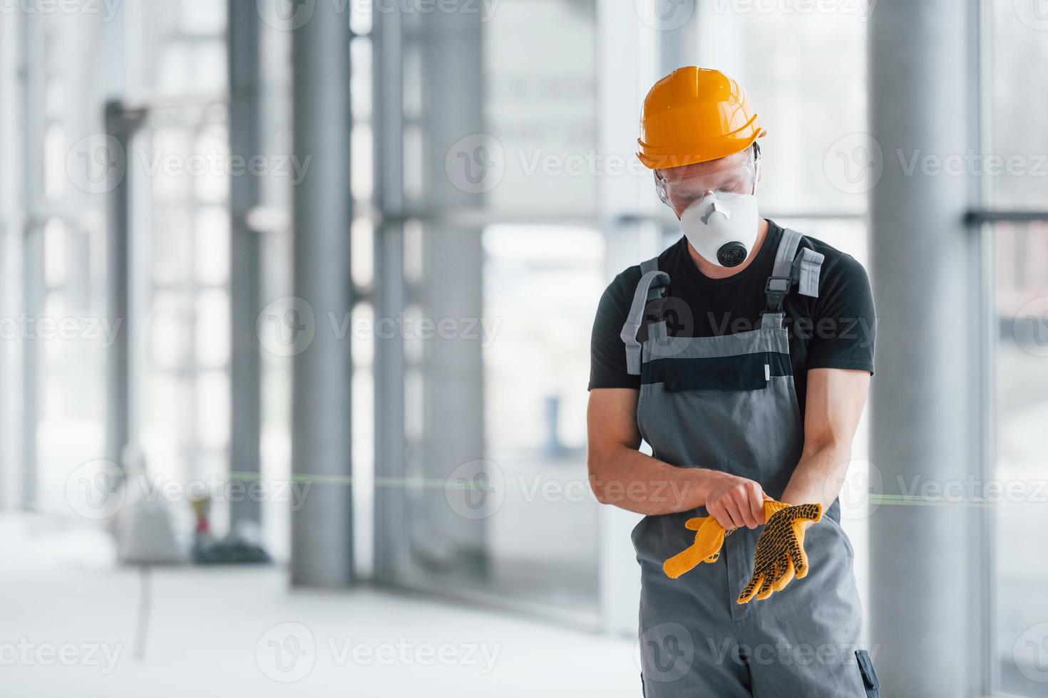 Man in grey uniform preparing for work indoors in modern big office at daytime photo
