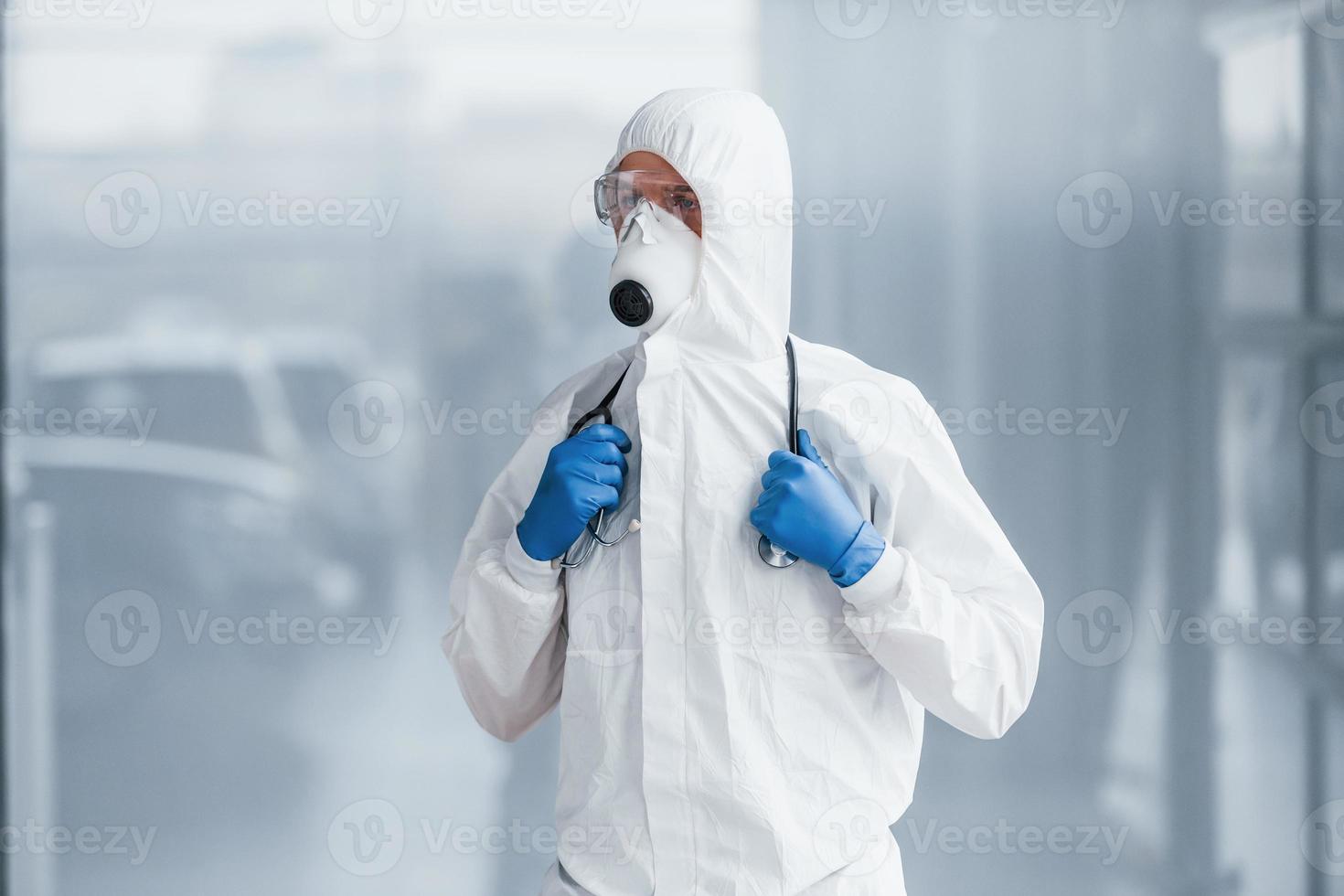 médico científico masculino en bata de laboratorio, anteojos defensivos y máscara foto