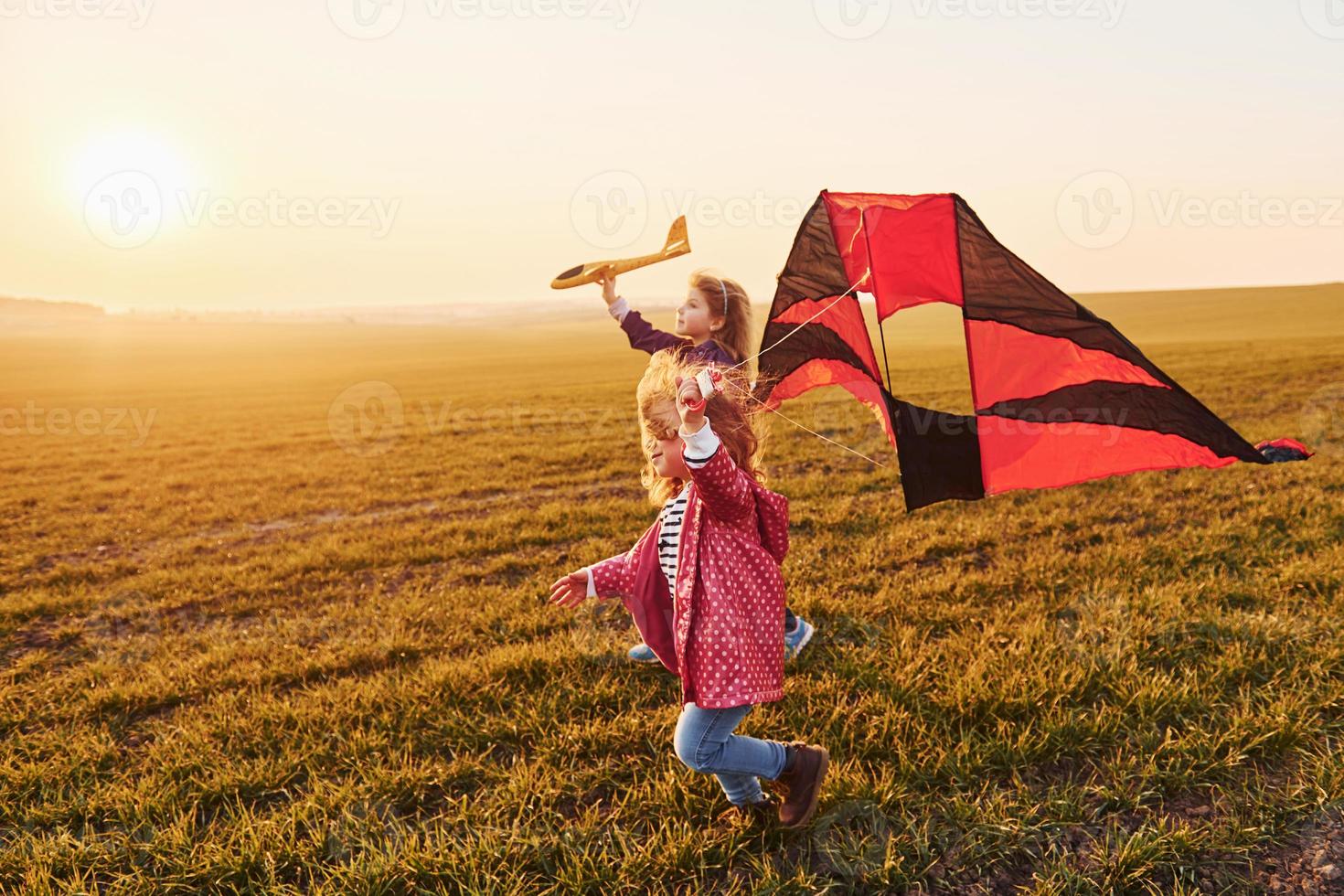 niña feliz corriendo con cometa en las manos en el hermoso campo a la hora del sol foto