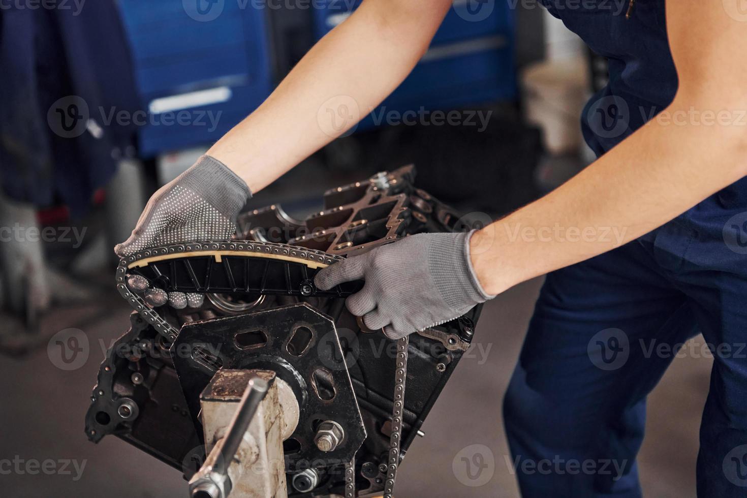 Close up view of professional repairman in garage that works with broken automobile engine photo
