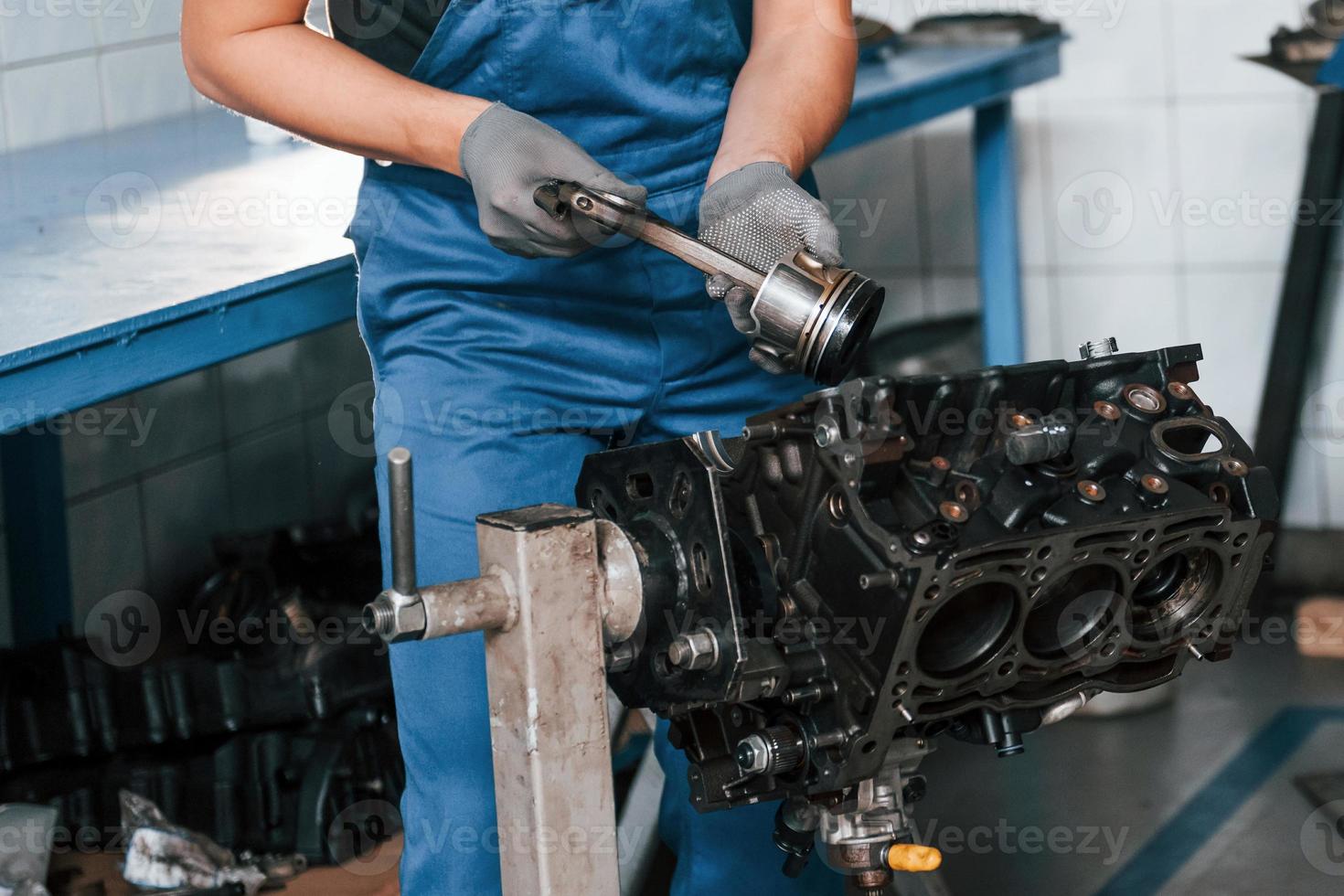 Professional repairman in garage works with broken automobile engine photo