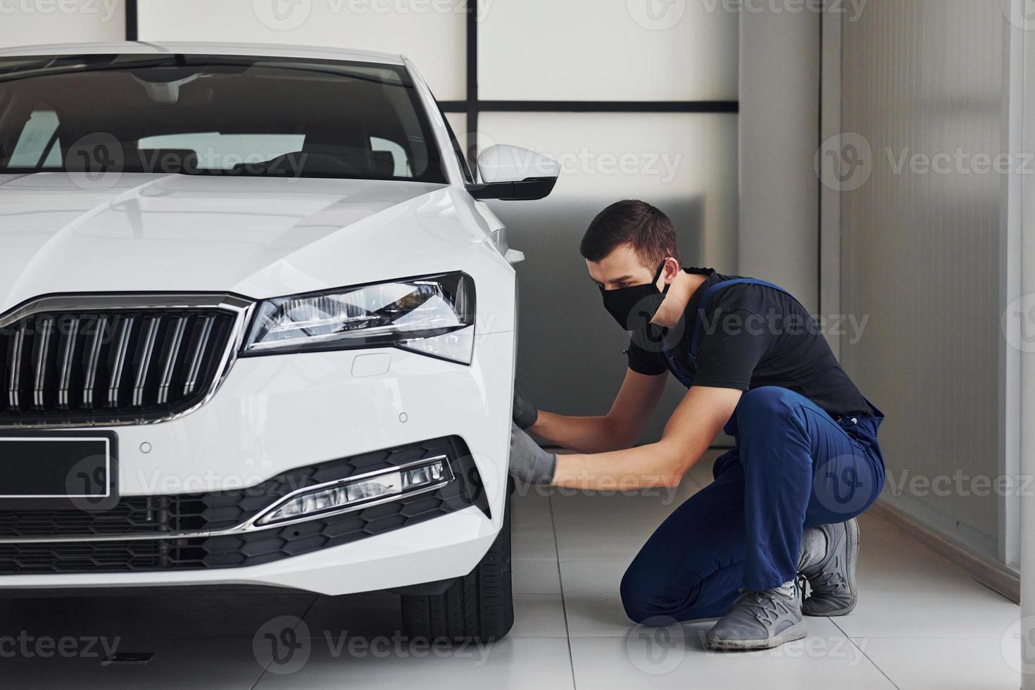 Man in blue uniform and black protective mask changing wheel photo