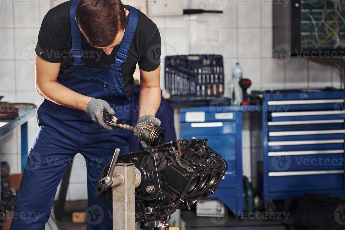 Professional repairman in garage works with broken automobile engine photo