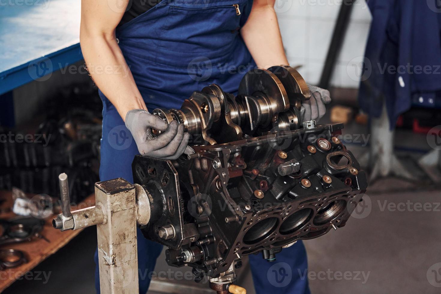 Professional repairman in garage works with broken automobile engine photo