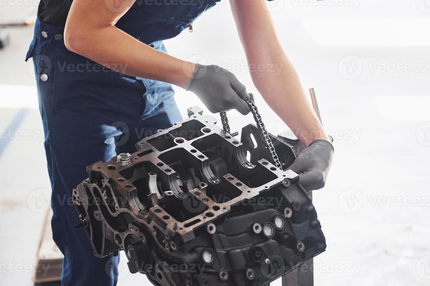 Professional repairman works with broken automobile engine photo
