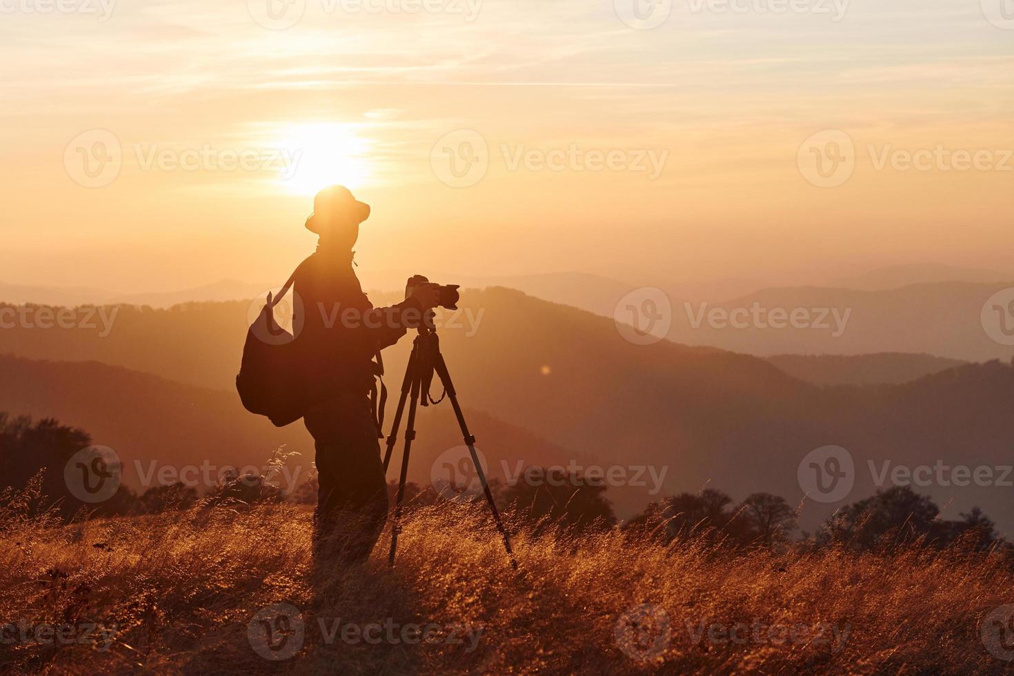 Male photographer standing and working at majestic landscape of autumn trees and mountains by the horizon photo