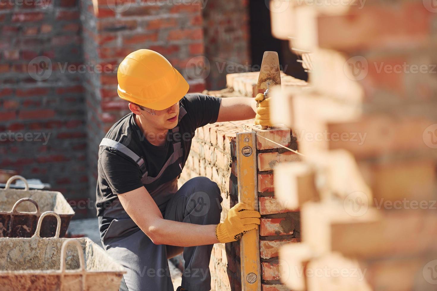 Measures of brick wall. Construction worker in uniform and safety equipment have job on building photo