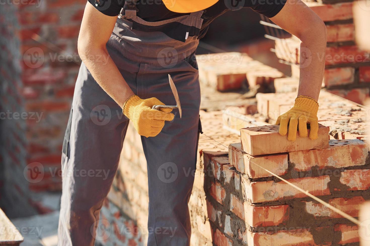 Measures of brick wall. Construction worker in uniform and safety equipment have job on building photo