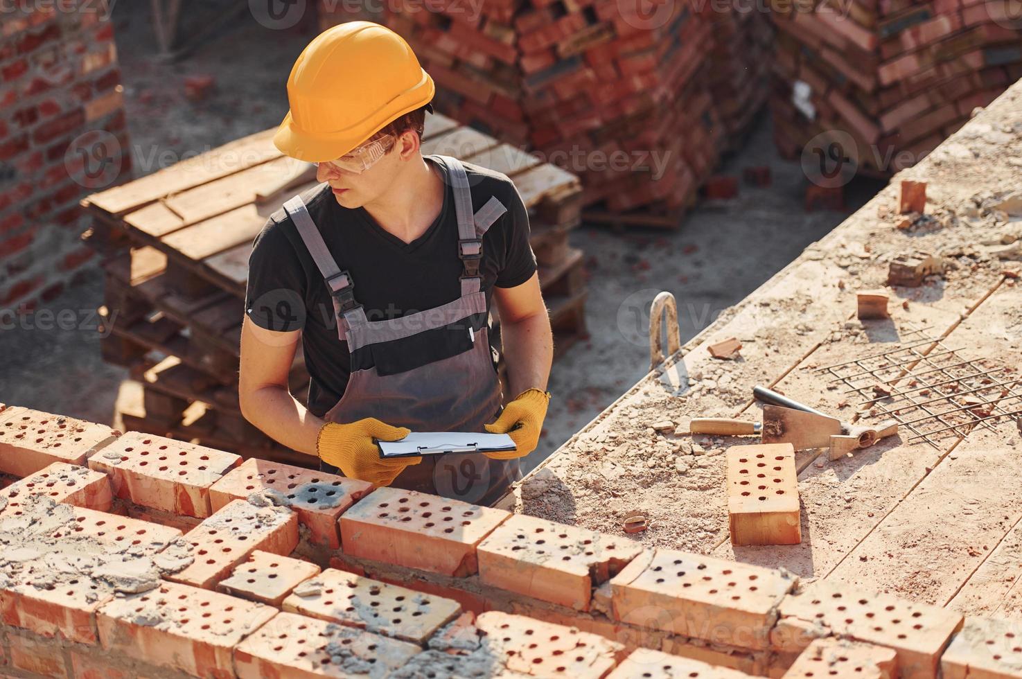 Holding plan in hands. Construction worker in uniform and safety equipment have job on building photo