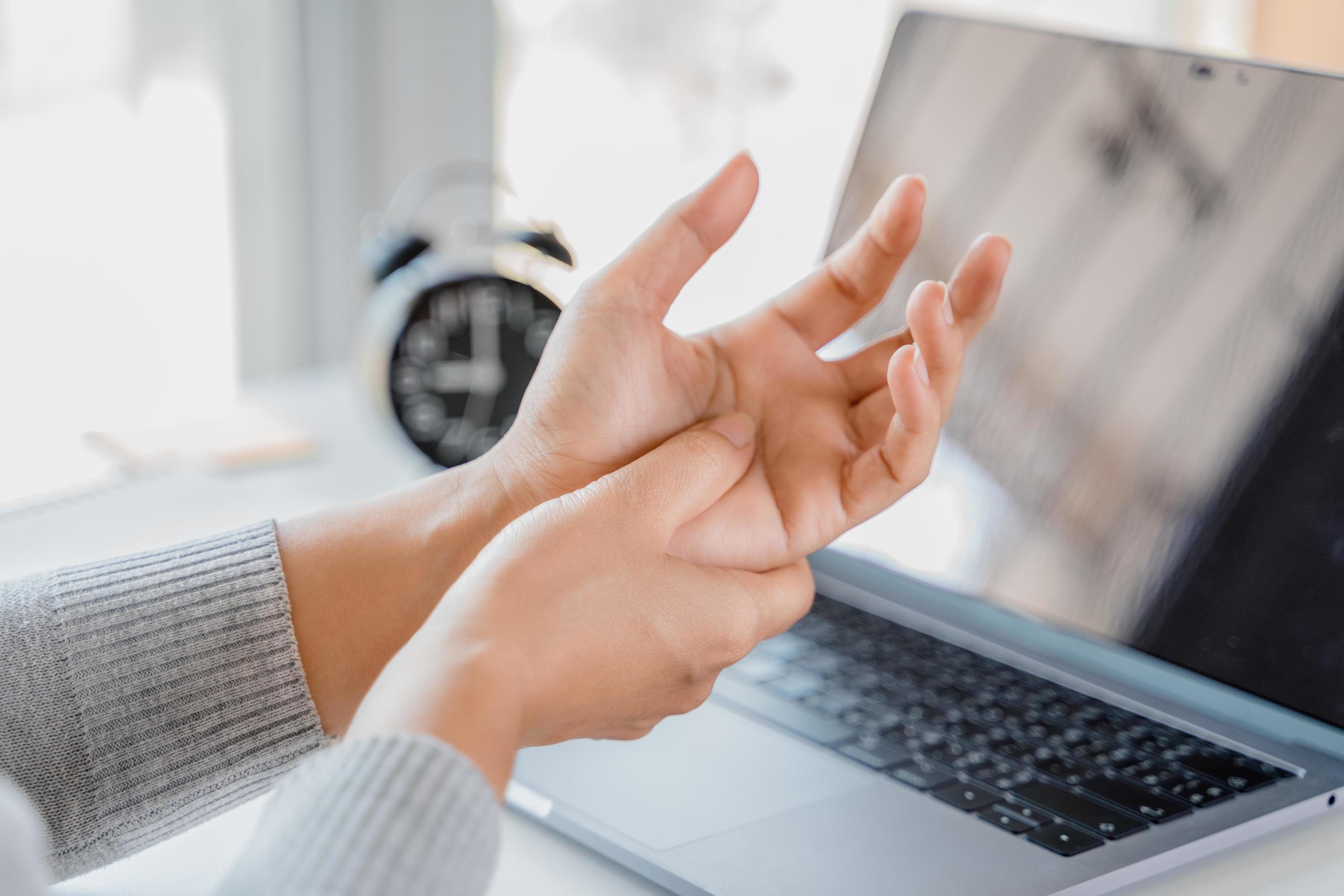 Closeup woman holding her hand pain from using laptop computer long