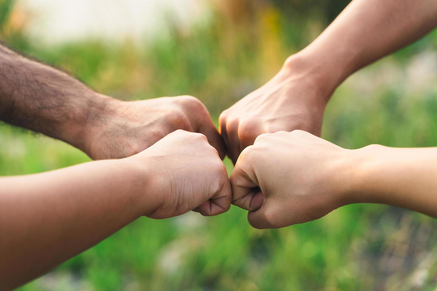 gente poniendo sus manos juntas. amigos haciendo golpes de puño en grupo. unidad y trabajo en equipo. amistad felicidad ocio asociación equipo concepto. foto