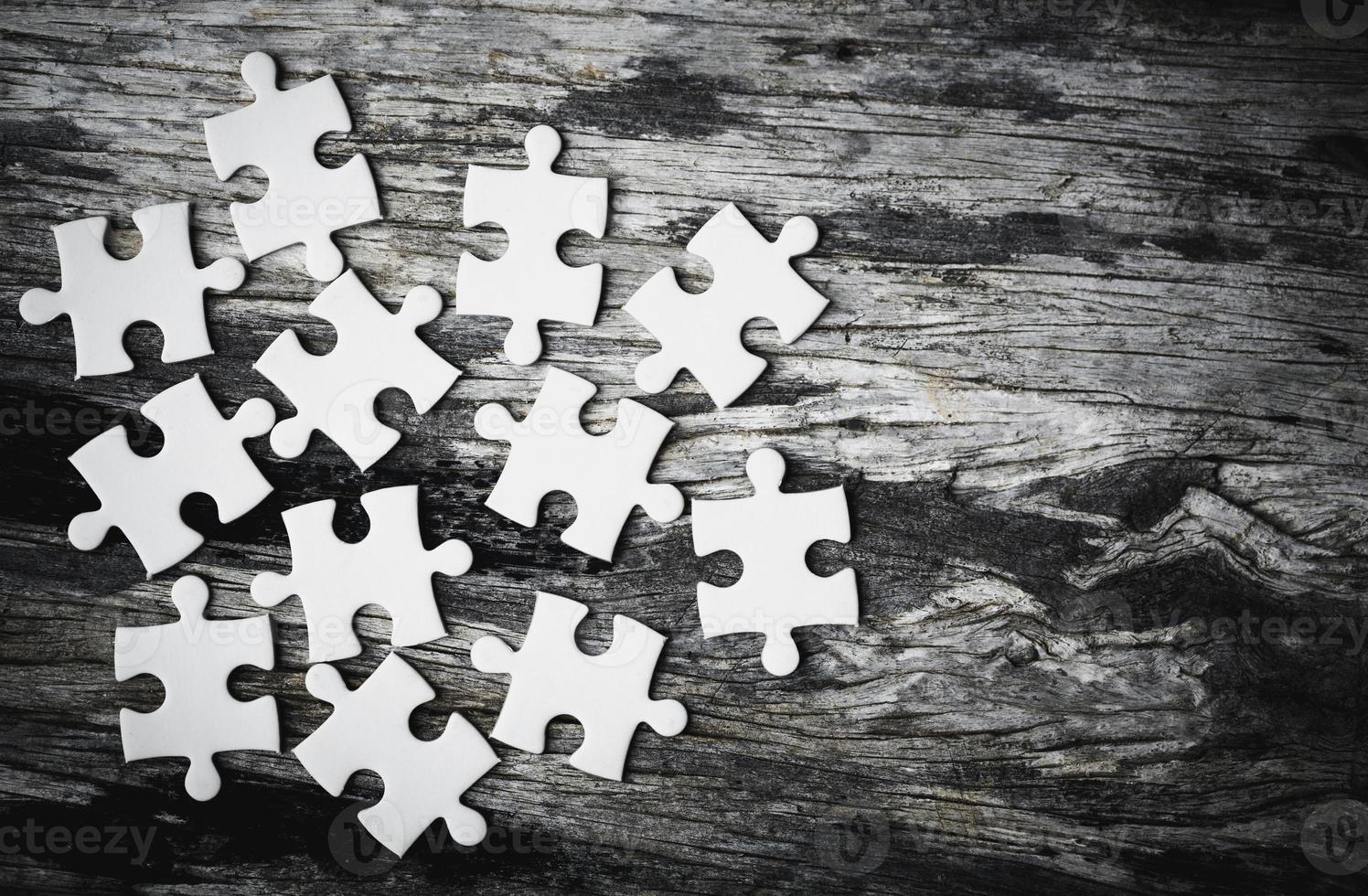 White details of jigsaw puzzle piece on wooden background. Concept of working together as a business team. The idea of getting involved, working for success. photo