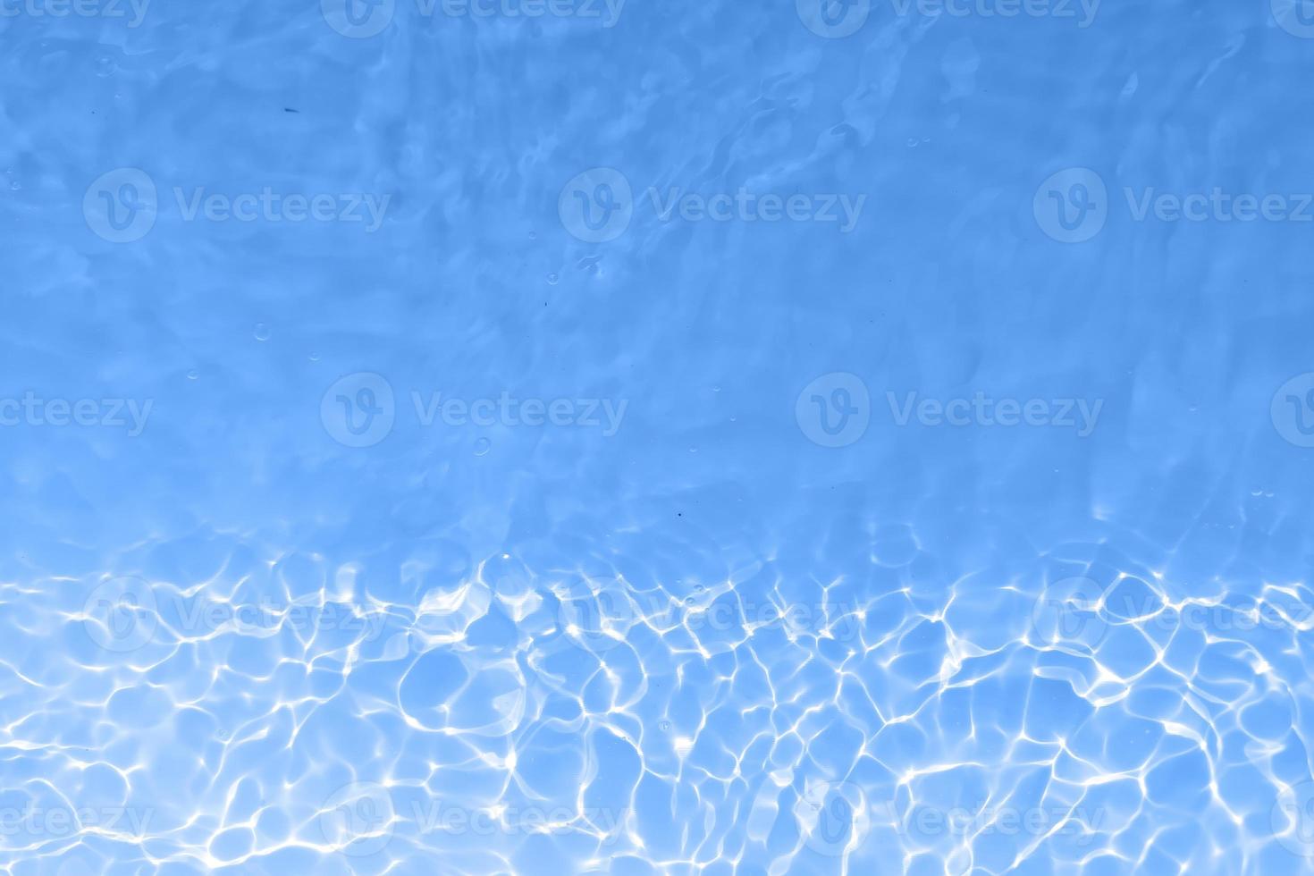 Defocus blurred transparent blue colored clear calm water surface texture with splashes and bubbles. Trendy abstract nature background. Water waves in sunlight with copy space. Blue watercolor shining photo