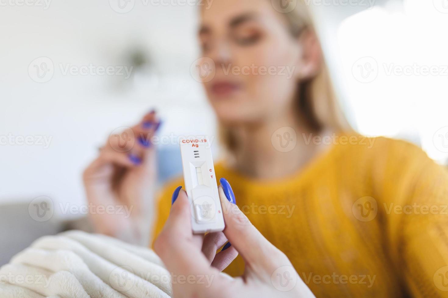 woman using cotton swab while doing coronavirus PCR rapid diagnostic test. Woman takes coronavirus sample from her nose at home. Young woman at home using a nasal swab for Antigen kit test COVID-19. photo