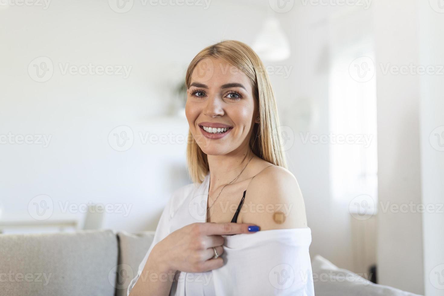 Woman pointing at her arm with a bandage after receiving the covid-19 vaccine. Young woman showing her shoulder after getting coronavirus vaccine photo