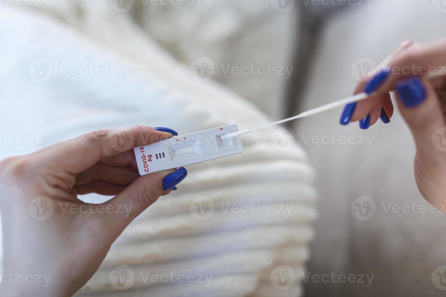 mujer joven sosteniendo un hisopo autoadministrado y un tubo médico para el coronavirus covid-19, antes de ser autoexaminado en casa foto