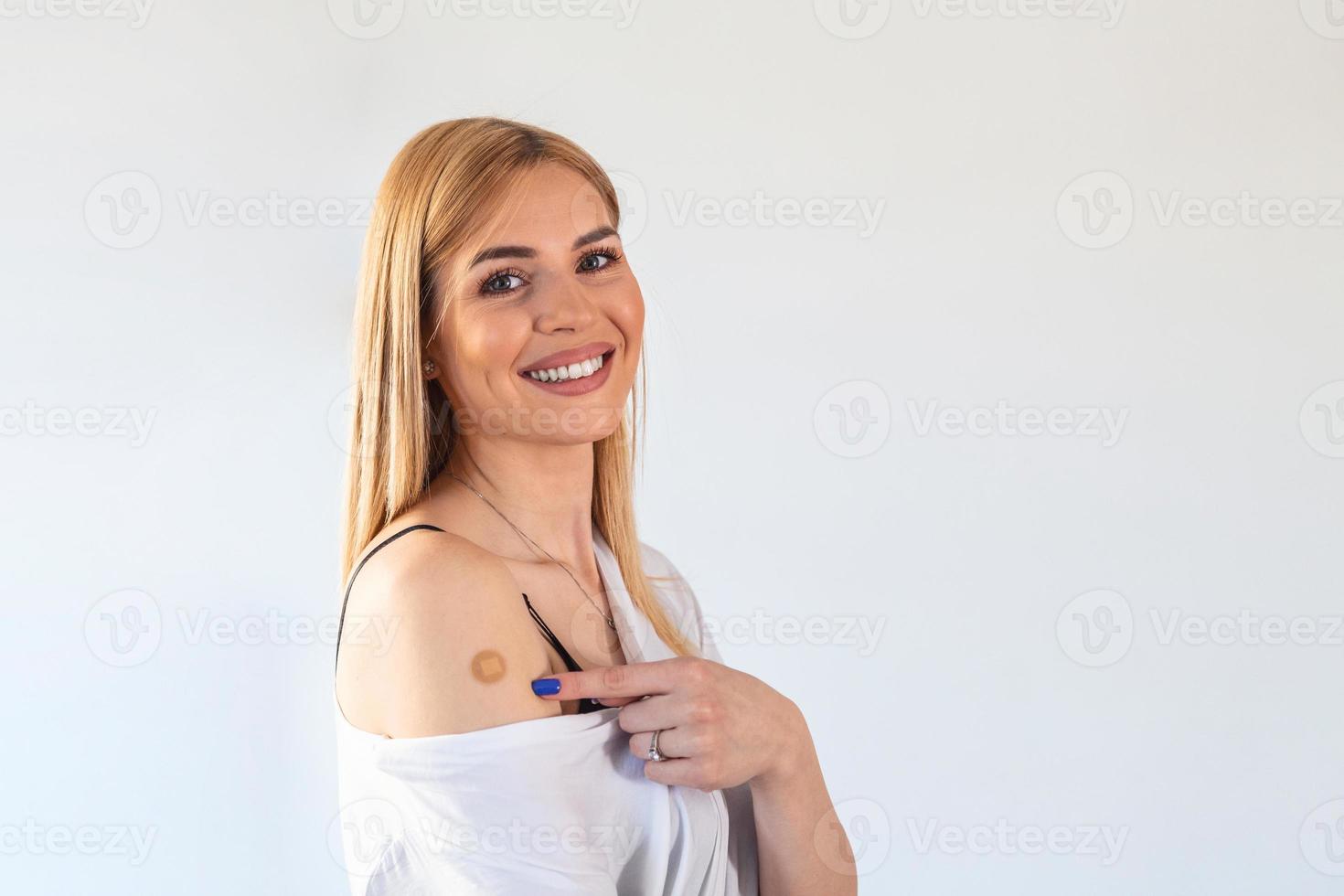 Woman pointing at his arm with a bandage after receiving the covid-19 vaccine. Young woman showing her shoulder after getting coronavirus vaccine photo