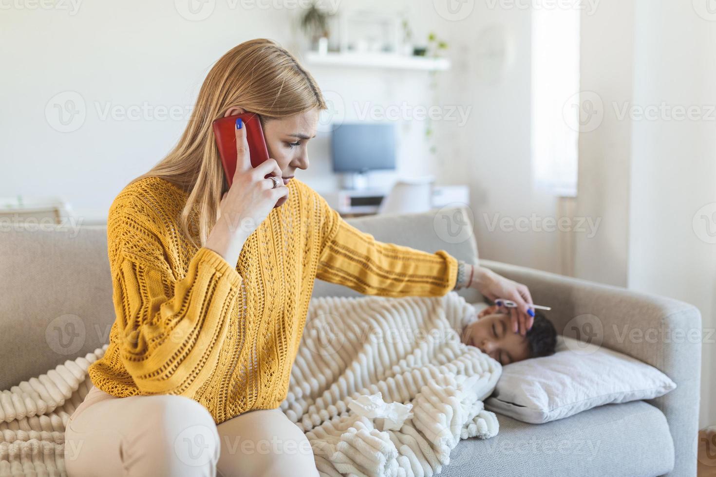 niño enfermo con termómetro acostado en la cama y la mano de la madre tomando la temperatura. madre revisando la temperatura de su hijo enfermo y llamando a un médico. niño enfermo con fiebre y enfermedad en la cama. foto