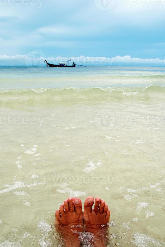 Legs of woman on a seashore with clear water and view on blue sky. Island Phi Phi, Thailand. photo