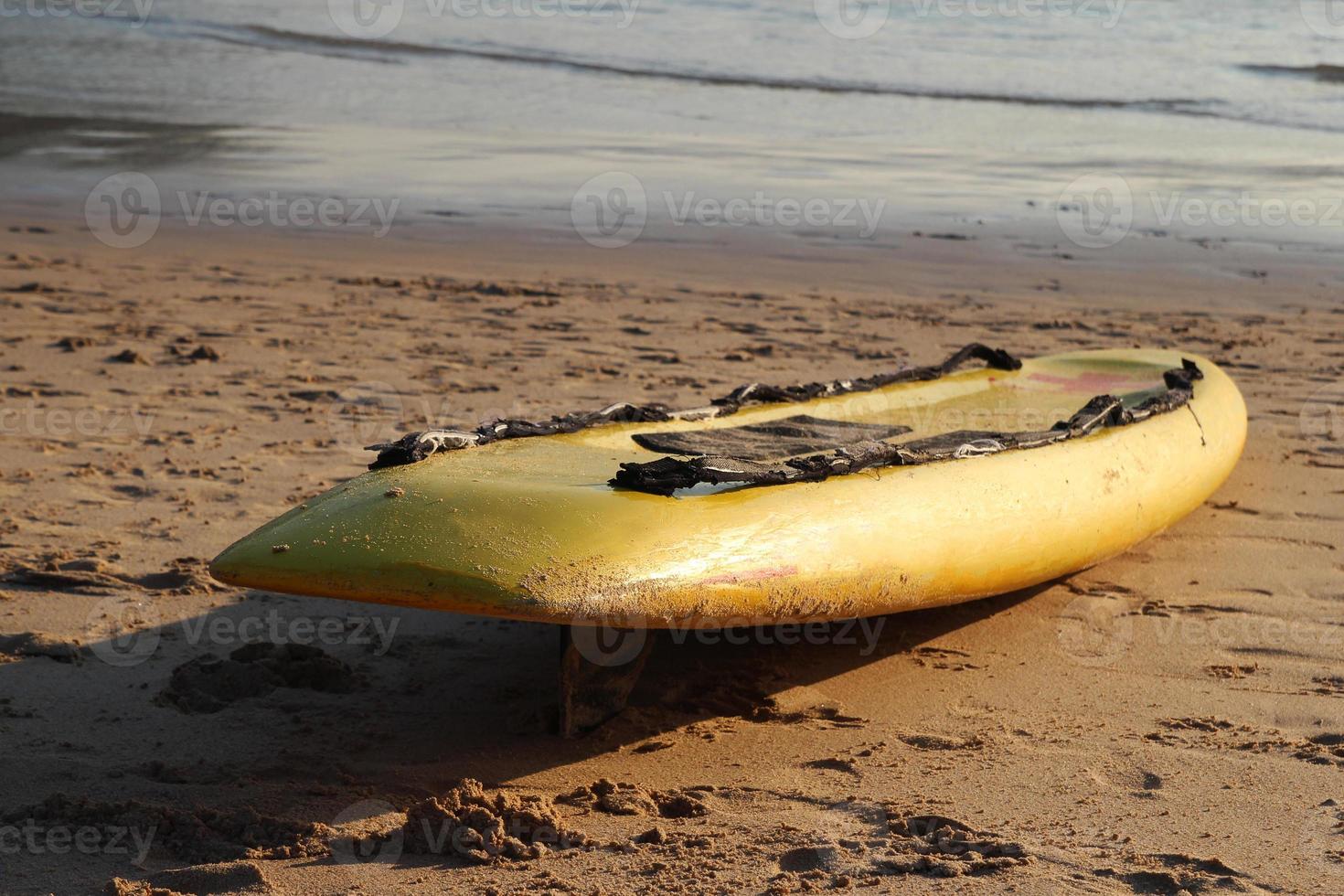 Travel to island Phuket, Thailand. Yellow surfboard closeup on the sand beach with sea on background. photo