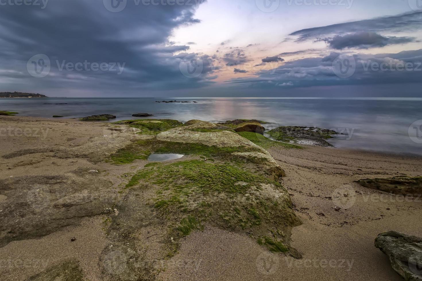 beauty long exposure rocky beach seascape and sea rocks with algae photo