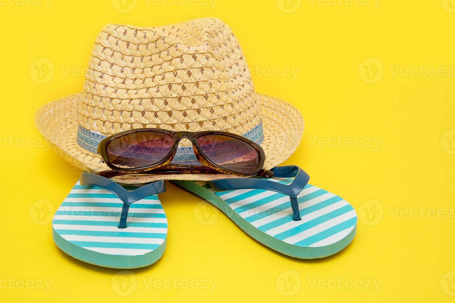 hat with sunglasses and striped flip flops on a yellow background photo